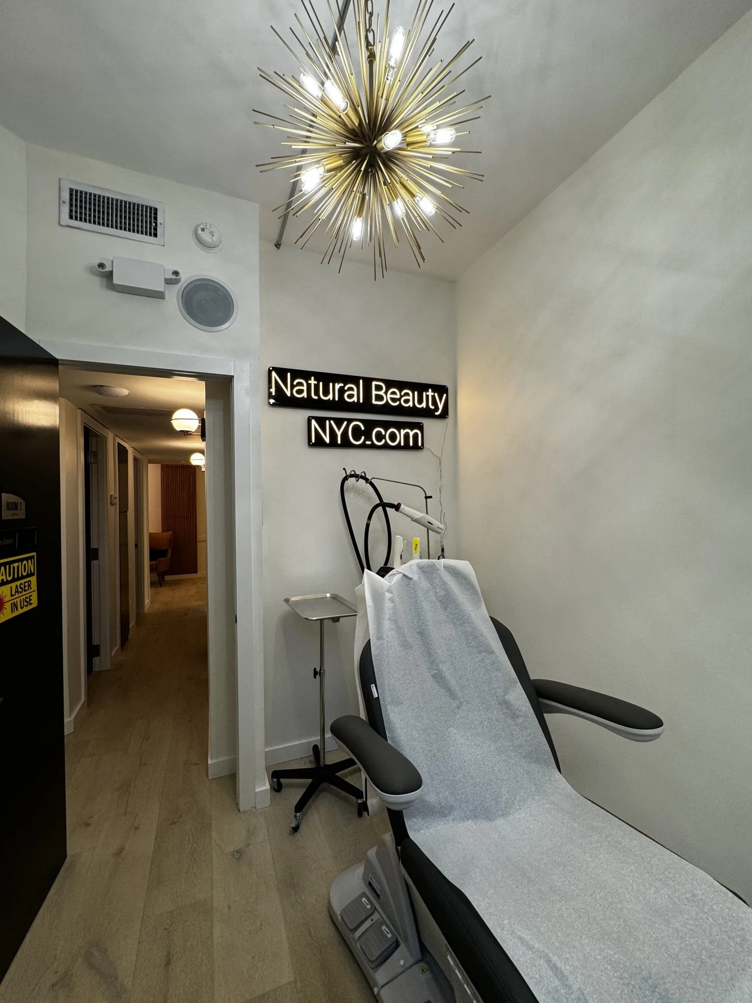 Natural Beauty Fifth Avenue treatment room with laser equipment and neon signage in New York clinic